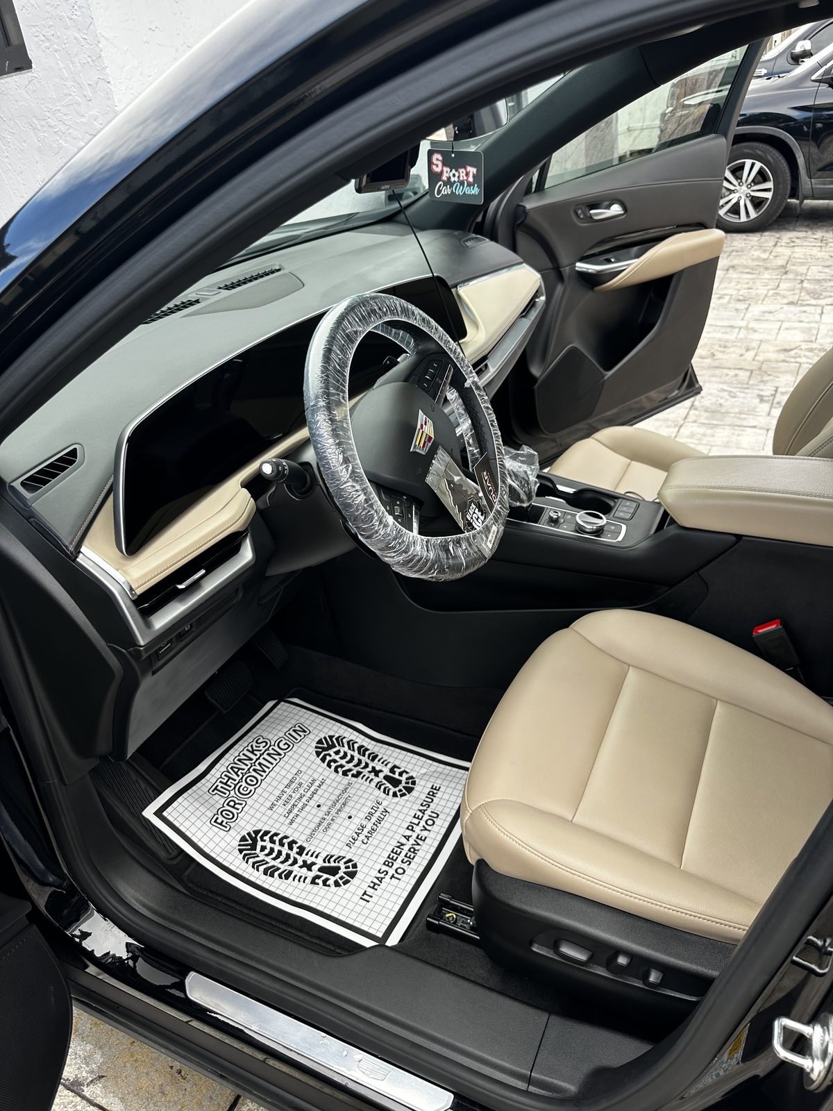 Finished cream leather interior of a Cadillac after a full detail, with clean dashboard, console and floor